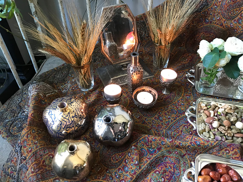 sofreh of mirror, candles, bunches of wheat and ceramic pomegranates