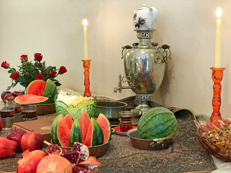 tea paraphernalia, candleholders, crystal sugar, whole and cut watermelons, pomegranates and apples