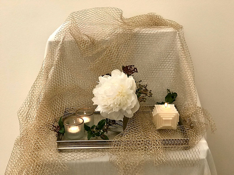 white peony, sprigs of Viburnum tinus and candle