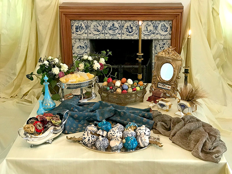 sofreh with blue and gold, candles, eggs, pomegranates