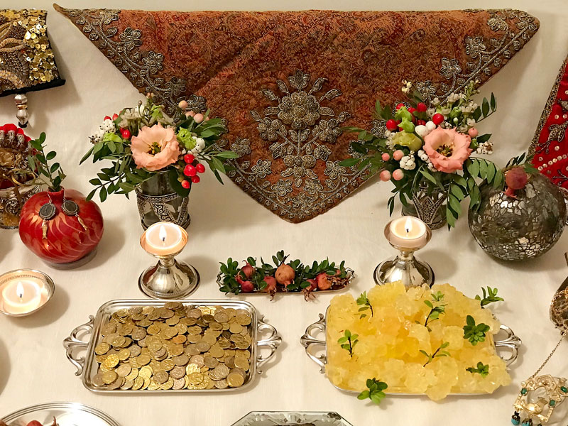 embroidered antique Persian textile with small trays containing gilded coins
