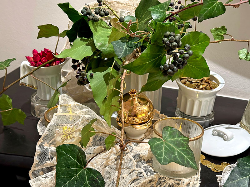 gilded coins, dried rosebuds, ivies, and pomegranate