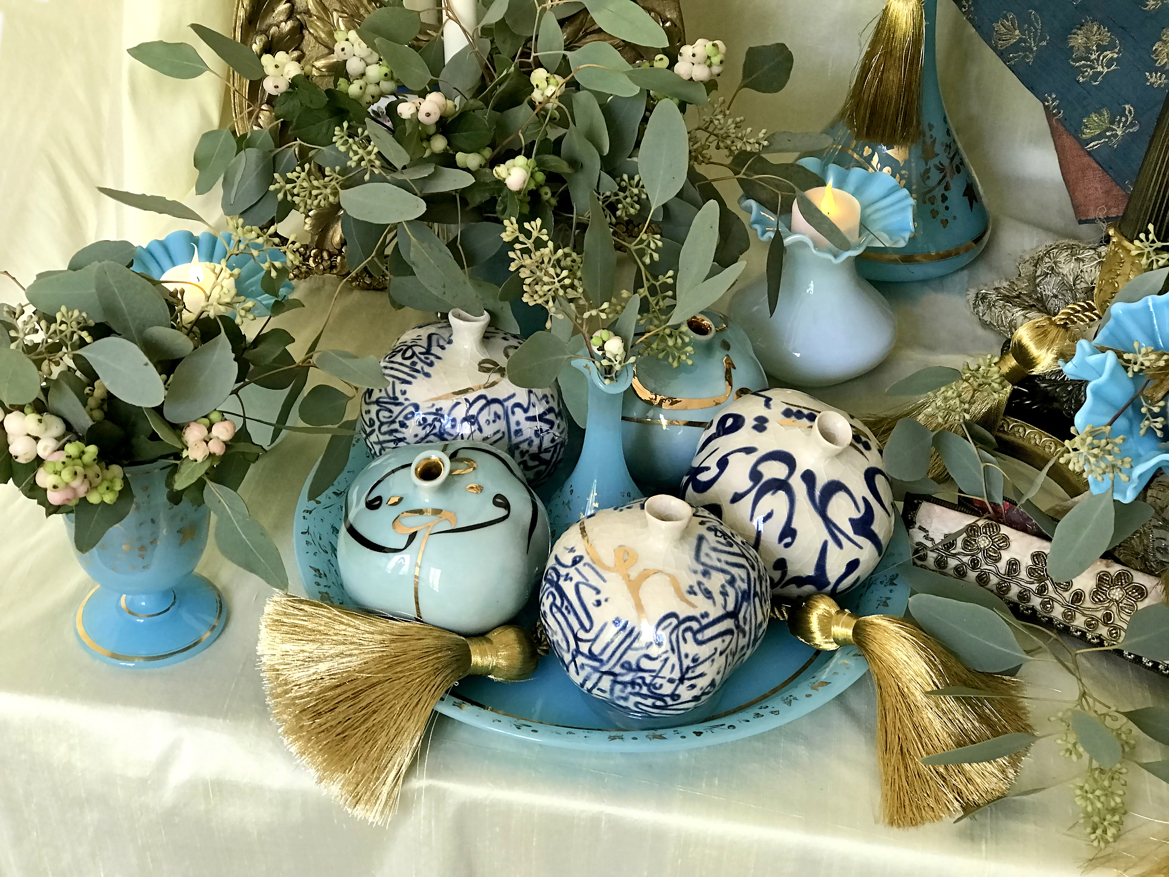 Ceramic pomegranates in gold, blue and white tones, and a miniature flask of Persian rosewater