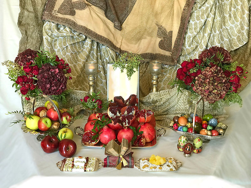 Sofreh containing apples, pomegranates, and flowers