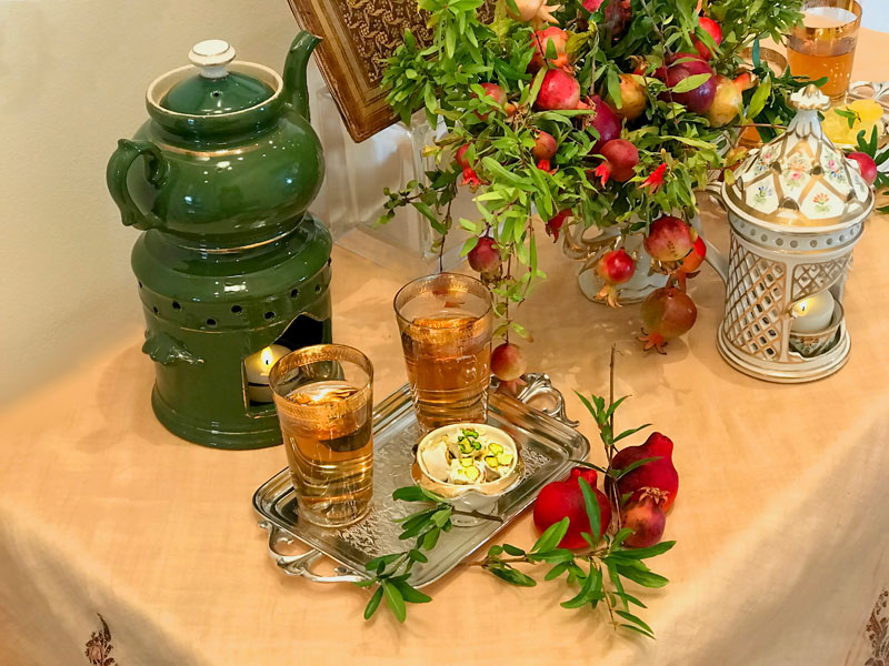 gold-rimmed glasses of tea together with Persian pistachio nougats (gaz), placed on a miniature antique tray