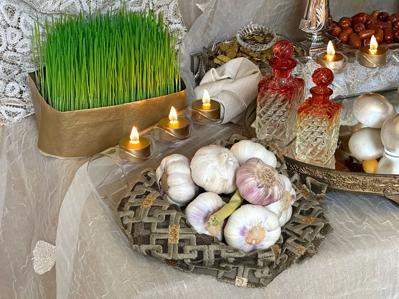 seven fresh garlic bulbs, placed on a bed of draped lace-like fine textile with metallic-gold accents