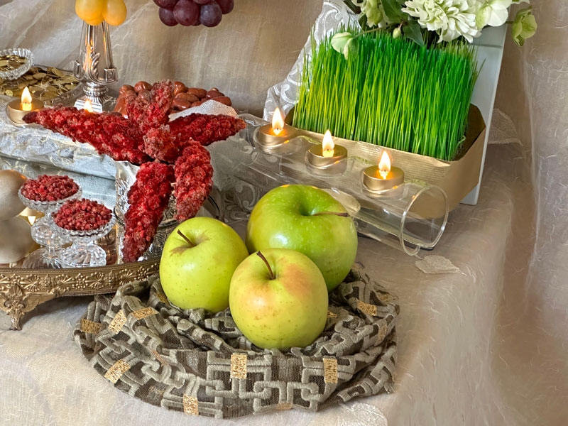 large, splendid, shiny green apples, placed on a bed of draped lace-like fine textile with metallic-gold accents.