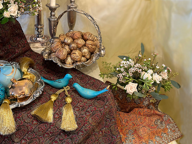 antique silver-plated basket with gold nuts, ceramic birds, and flowers