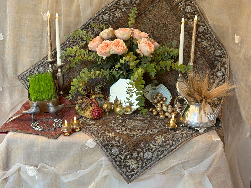 A sheer textile with leaf motifs forms the backdrop overlayed by two lengths of elaborately embroidered antique Persian textiles