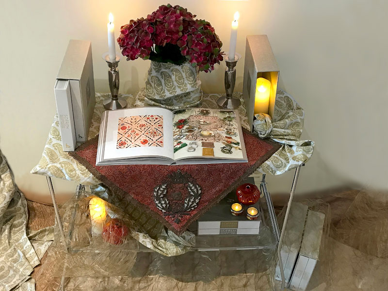 several volumes of the book with a length of red textile, red hydrangeas and ceramic pomegranates